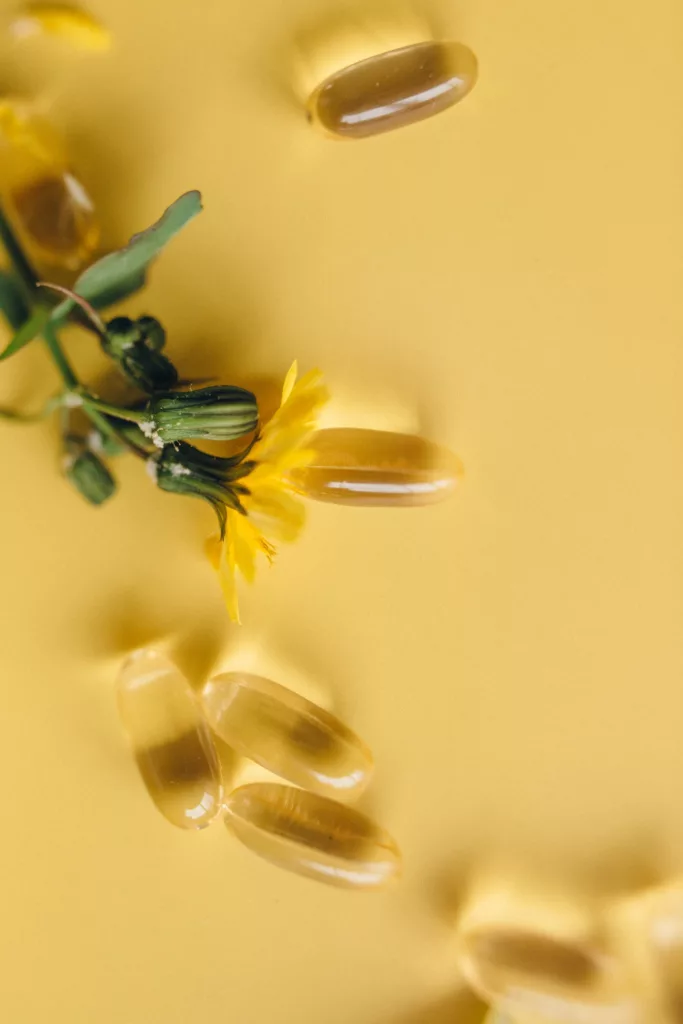 Softgels and a Dandelion Flower on Yellow Surface